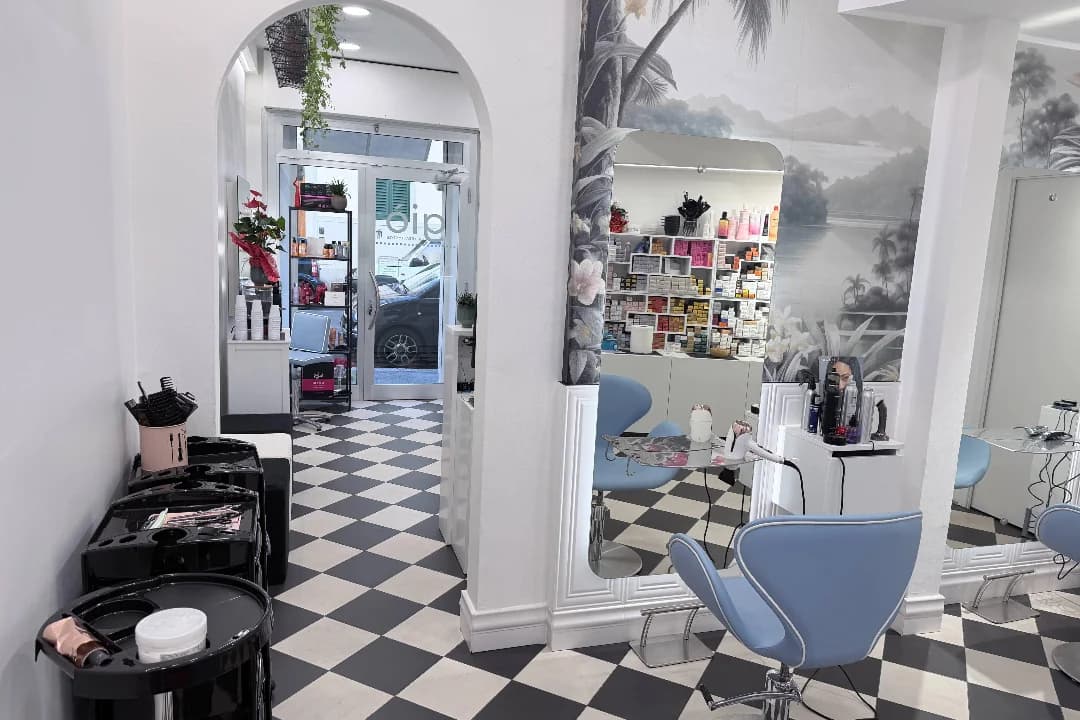 Vista d’insieme del salone: l’arco, le postazioni con la carta da parati tropicale, il pavimento a scacchi e la vetrina sul fondo
