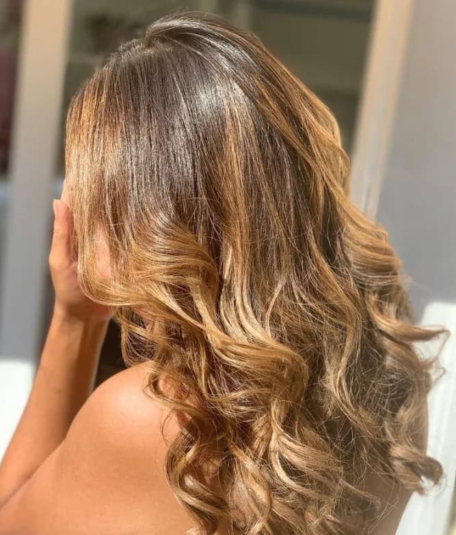 Capelli lunghi mossi, castano caramello con schiariture sulle lunghezze